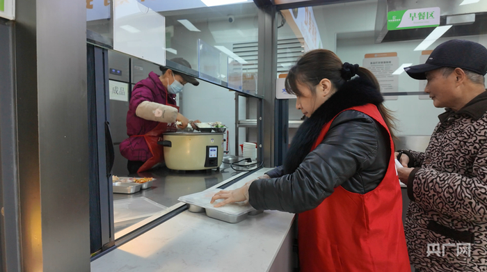 邹伟红在社区食堂为老人打饭（央广网记者黄珂岚 摄）