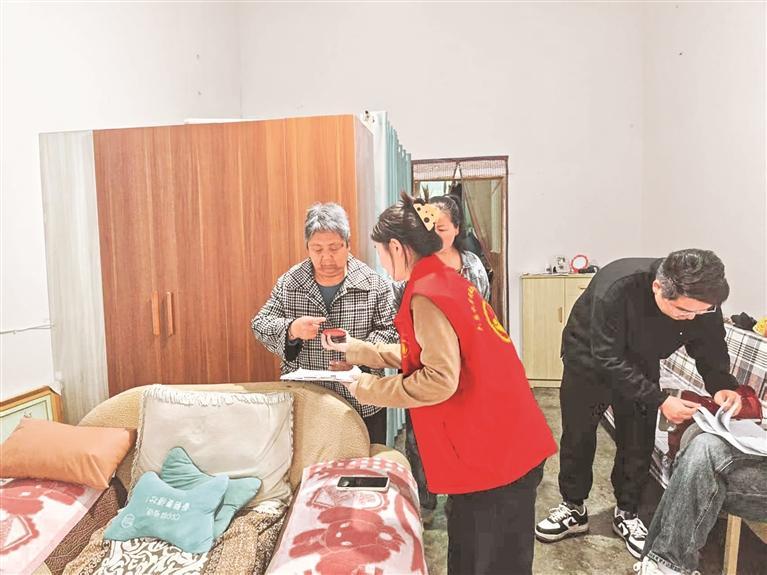 吕国润（红马甲）到老人家中核验情况。 受访者供图